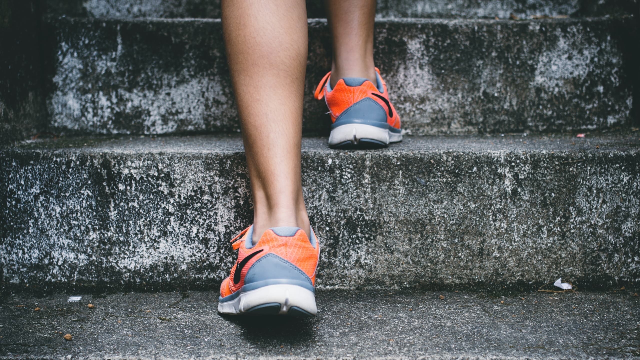 Person walking up concrete steps in orange and blue trainers
